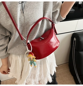 Detailed close-up of a red glossy crescent shoulder bag with metallic buckle and charm