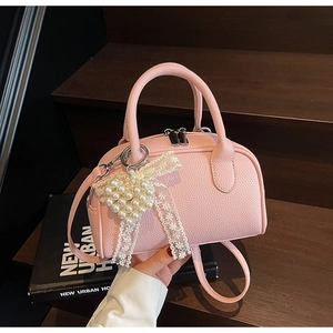 Dettaglio borsa bowling in pelle rosa martellata con ciondolo a cuore e perle