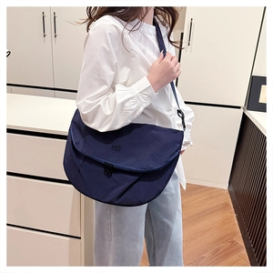 Detailed view of dark blue nylon tote bag with MG embroidery and adjustable strap