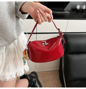 Close-up of bright red oil wax leather handbag featuring a silver lock and pearl charm