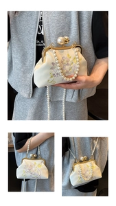 Close-up of floral embroidery on ivory satin bag with large pearl clasp and chain