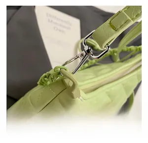 Detail view of the silver metal lobster clasp and quilted light green leather bag strap