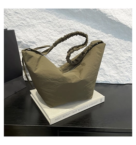 Detail of olive green dumpling bag featuring pleated scrunchie shoulder strap design