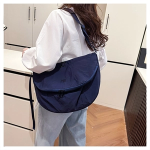 Detail view of navy blue nylon crossbody bag featuring ME embroidery and adjustable strap