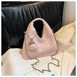 Detail of pink wrinkled patent leather bag with fashion text and heart chain charm