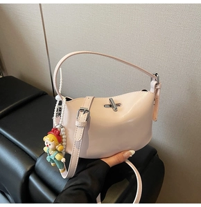 Detail of light pink faux leather handbag featuring silver twist lock and cute doll charm