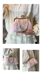 Close-up of pink evening bag with floral embroidery, pearl clasp and metal chain