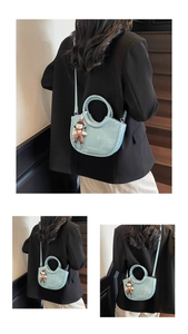Close-up of light blue leather half-moon bucket bag with a doll charm and silver logo