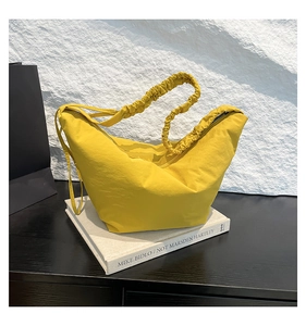 Detail of a bright yellow pleated shoulder strap and fabric texture on a hobo bag