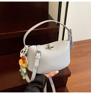Close-up of light blue patent leather handbag with silver twist lock and pearl doll charm