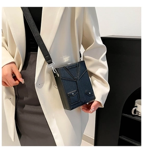 Detail of black blazer-shaped crossbody bag with silver twist lock and leather strap