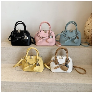 Detailed view of fashionable shell bags in five colors with heart pendants on stone steps
