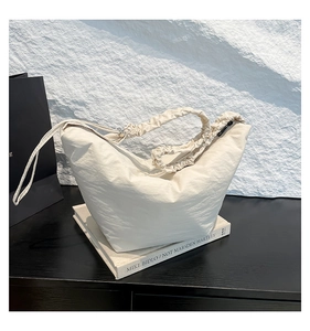 Detail of cream pleated shoulder strap on nylon crescent dumpling crossbody bag