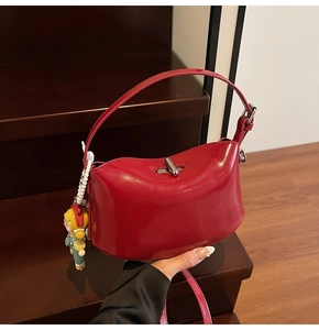 Close-up of bright red patent leather handbag with silver lock and cartoon doll charm