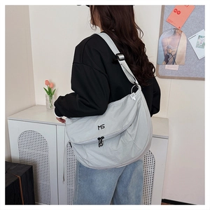 Detail view of the light grey nylon tote bag with embroidered MG logo and adjustable strap