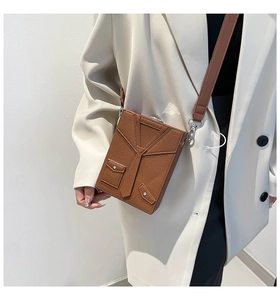 Detail view of brown leather crossbody bag featuring unique suit collar and tie design