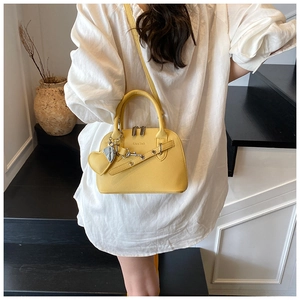 Detail of yellow lychee leather shell bag with heart charm and silver metal logo