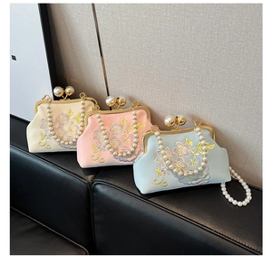 Detail of floral embroidery on satin evening bags with pearl clasps and handles