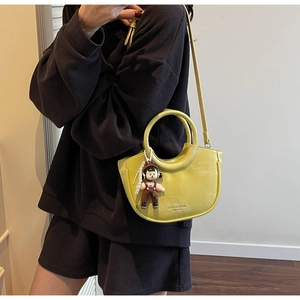 Detail of lemon yellow half-moon bucket bag with round handle and cute cartoon charm