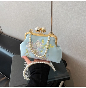 Detailed embroidery on light blue satin evening bag with elegant pearl clasp and chain