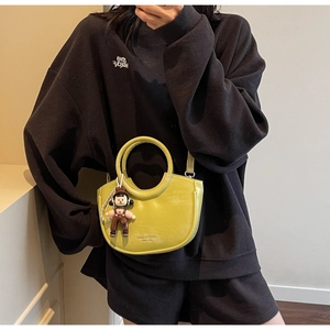 Detail of lemon yellow crescent bucket bag with cute doll charm and pearl chain decoration