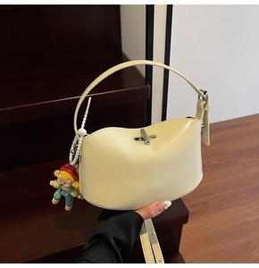 Detail view of yellow wave-edge tote bag with silver metal twist lock and cute charm