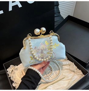 Detailed embroidery on light blue silk evening bag with pearls and golden frame closure