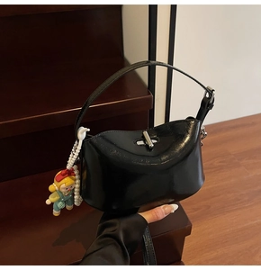 Close-up of black glossy oil wax leather handbag with silver twist lock and doll charm