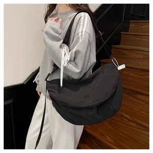 Detail of black nylon crossbody tote bag showing MS logo embroidery and wide strap