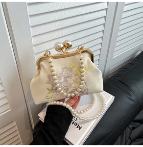 Close-up of elegant floral embroidery and pearl clasp on ivory white qipao evening bag