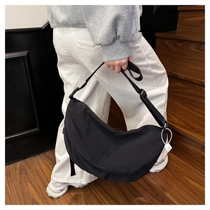 Close-up of black nylon crescent bag with MS logo and adjustable strap worn by model