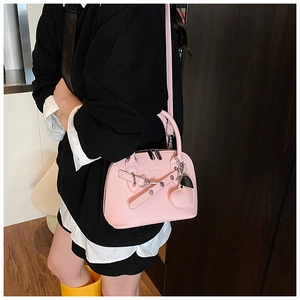 Pink heart shell bag detail featuring litchi grain texture and metallic heart pendant