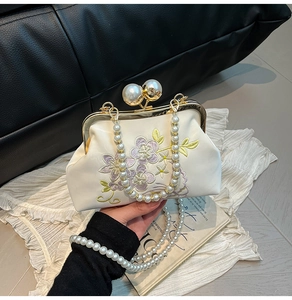 Close-up of floral embroidery and pearl handle on elegant vintage evening clutch bag