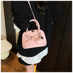 Detail of pink shell-shaped crossbody bag with heart charm and lychee texture leather