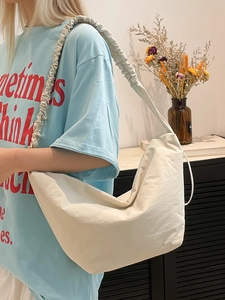 Minimalist beige dumpling bag with ruched shoulder strap shown on model for daily use