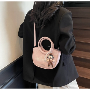 Detail of light pink bucket bag with a cartoon bear charm and pearl chain decoration