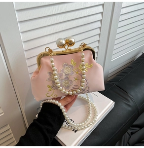 Detailed close-up of pink satin evening bag with floral embroidery and pearl clasp