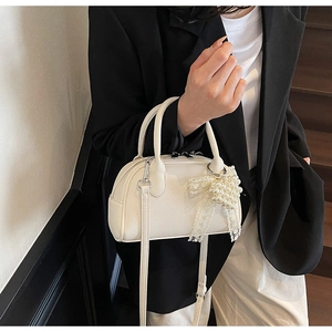 Dettaglio della piccola borsa bianca con ciondolo a fiocco di perle e pizzo elegante