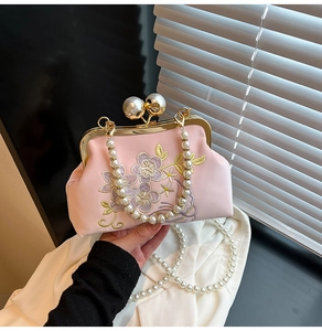 Close-up of pink silk evening bag featuring floral embroidery and pearl clasp