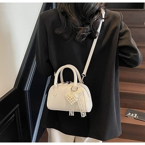 Dettaglio borsa crema con ciondolo a cuore di perle e fiocco in pizzo elegante