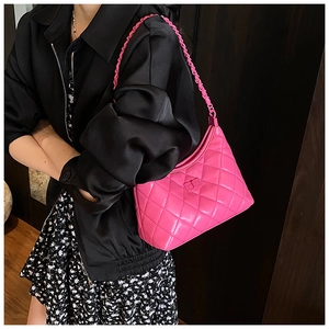 Detail view of the fuchsia quilted handbag with chain strap on a model shoulder