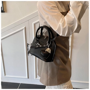 Detail of black shell bag showing lychee grain leather and heart-shaped metal charm