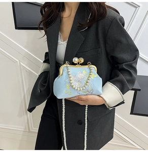 Detail of elegant light blue evening bag with floral embroidery and pearl chain strap