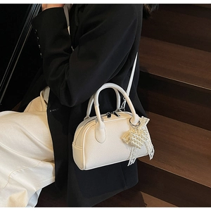 Dettaglio borsa in pelle bianca con ciondolo a cuore di perle e fiocco di pizzo bianco