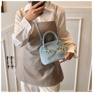 Close-up of sky blue shell bag with lychee texture leather and heart pendant