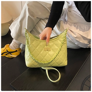 Close-up of light green quilted shoulder bag with metal turn-lock and chain handle