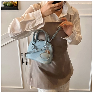 Close-up of light blue shell bag in lychee pattern leather with a silver heart pendant