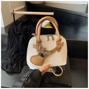 Detail of Boston shell bag in white litchi leather with heart charm and dual handles