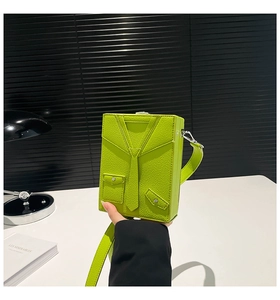 Detail of neon green suit-shaped box bag featuring faux leather texture and a tie design