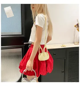 Pale yellow mini crossbody bag shown with a stylish red skirt and headphones outfit
